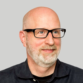 A bald man with eyeglasses and a short white beard gazes away from the camera.